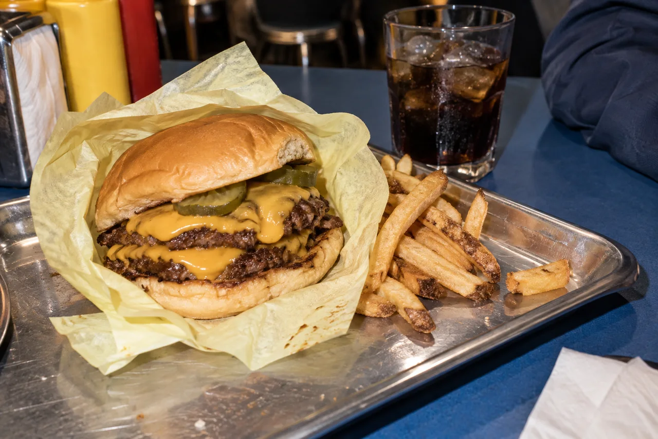 Double smash burger et frites sur un plateau en métal.